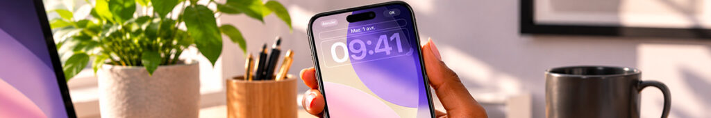 Smartphone tenu en main sur un bureau, écran allumé sans encoche visible